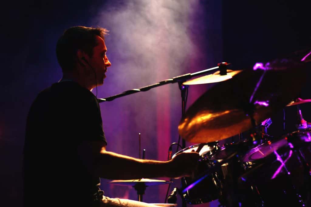 Drummer playing drum kit on smoky stage