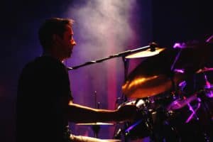 Drummer playing drum kit on smoky stage